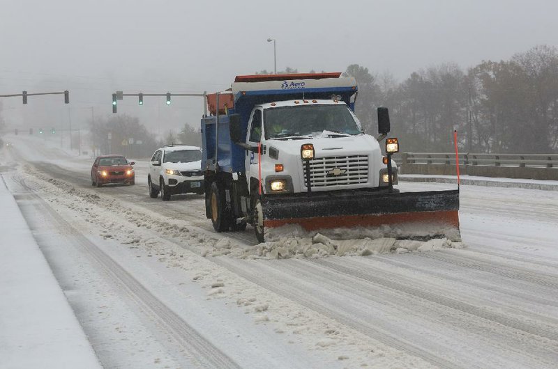 A Little Rock Street Department truck plows Barrow Road on Friday morning, leading vehicles up the hill near Interstate 630. 