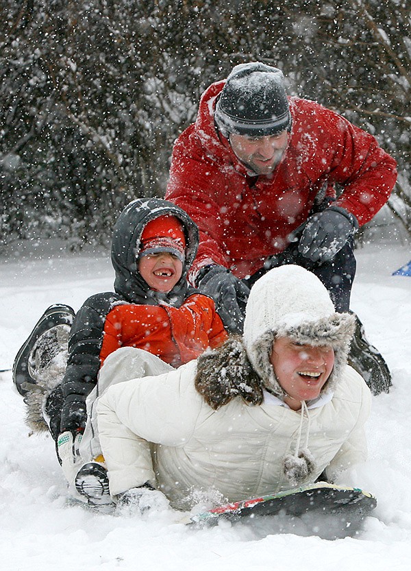 Darin Phelan gives his wife Jessica and son Lucas,6, a push Friday as they begin there tandem slide down the snow covered hill north of Reynolds Razorback Stadium in Fayetteville. The Phelans, which with daughter Kennedy, 8, and son Tyler, 10, got an early start on the snow-driven activities.
SLEDDING AND SMILES 