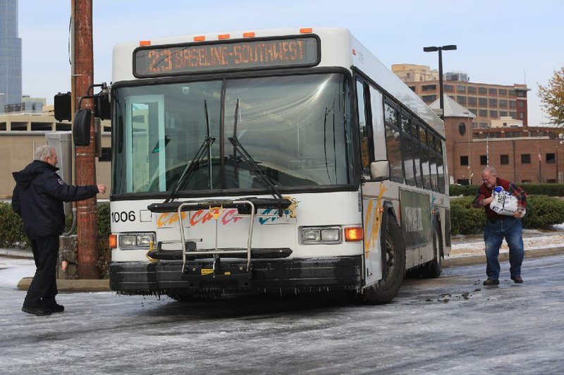 Central Arkansas Transit Authority officials (top) work on getting a city bus unstuck from the ice at East Fourth and Cumberland streets in Little Rock on Saturday. The interstates and some main roads were fairly clear in Little Rock and North Little Rock, but many side roads still were iced over.