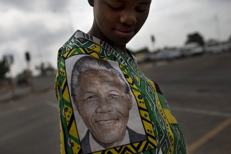 A woman wears a Nelson Mandela printed piece of fabric in Soweto, Johannesburg, South Africa, Sunday, Dec. 8, 2013. South Africans flocked to houses of worship for a national day of prayer and reflection to honor former President Nelson Mandela, starting planned events that will culminate in what is expected to be one of the biggest funerals in modern times. (AP Photo/Bernat Armangue)