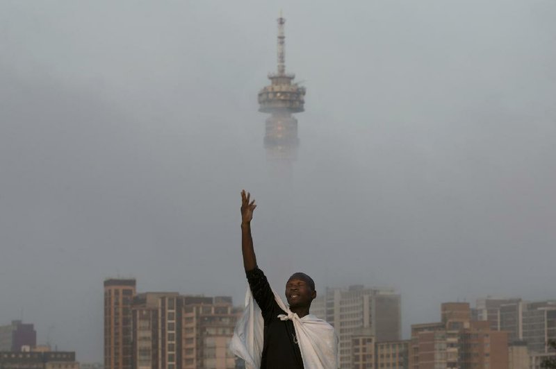 A Christian worshipper prays on a hill overlooking the city of Johannesburg, South Africa, Sunday, Dec. 8, 2013. South Africans flocked to houses of worship for a national day of prayer and reflection to honor former President Nelson Mandela, starting planned events that will culminate in what is expected to be one of the biggest funerals in modern times. (AP Photo/Bernat Armangue)