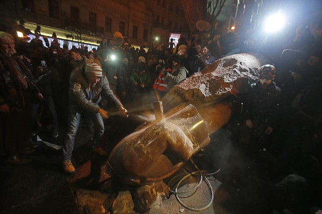 An anti-government protester smashes the statue of Vladimir Lenin with a sledgehammer in Kiev, Ukraine, Sunday, Dec. 8, 2013. Anti-government protesters have toppled the state of Bolshevik leader Vladimir Lenin in central Kiev amid huge protests gripping Ukraine. The chaotic protest further raised tensions in the Ukrainian capital. (AP Photo/Sergei Grits)