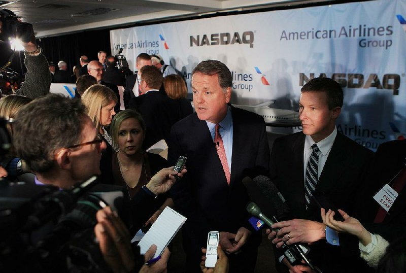 Douglas "Doug" Parker, chief executive officer of the newly formed American Airlines Group Inc., center, speaks to members of the media after remotely ring the opening bell of the Nasdaq MarketSite at American Airlines headquarters in Fort Worth, Texas, U.S., on Monday, Dec. 9, 2013. American Airlines Group Inc., formed today when AMR Corp. and US Airways Group Inc. combined, is poised to rise on confidence that the worldís largest carrier can avoid the pitfalls that dragged down other mergers. Photographer: Ben Torres/Bloomberg *** Local Caption *** Doug Parker