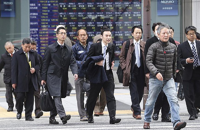 People walk by an electronic stock board of a securities firm in Tokyo, Monday, Dec. 9, 2013. Japan has revised its economic growth estimate for the last quarter downward after finding that capital investment slowed more than expected in July-September. (AP Photo/Koji Sasahara)