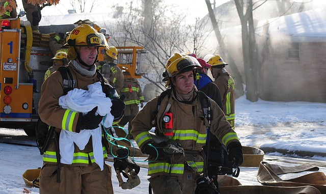 Springdale Firemen Nick Emerson and Nathan Warrell give a dog oxygen to an animal control officer after the dog was rescued from a house fire Tuesday.