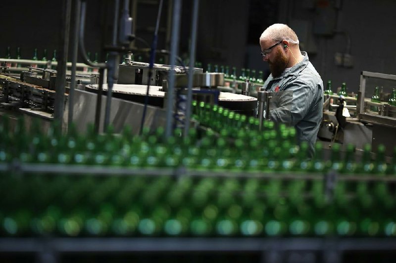 A worker keeps watch over glass bottles before they are filled with ginger ale at the Ale-8-One Bottling Co. in Winchester, Ky., on Friday. The Commerce Department said wholesale businesses increased their stockpiles in October by the most in two years. 