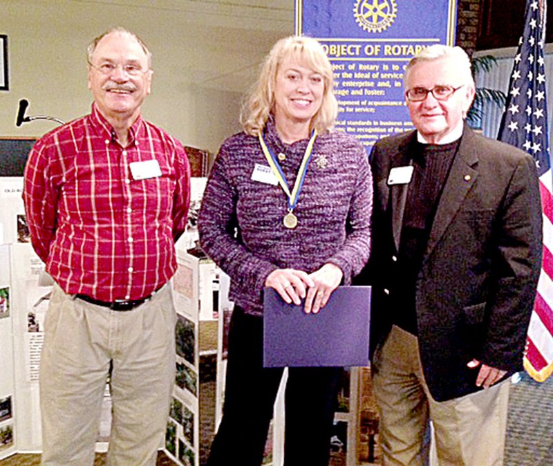 Submitted Sherry Hughes, center, receives a Paul Harris Fellowship from her husband, Steve, right, at a recent meeting of the Bella Vista Sunrise Rotary Club. Club President Mike Moles presided ov...