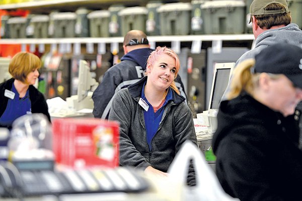 STAFF PHOTO ANTHONY REYES 
Jessica Buckles, cashier at Academy Sports, assists a customer Tuesday in Rogers.