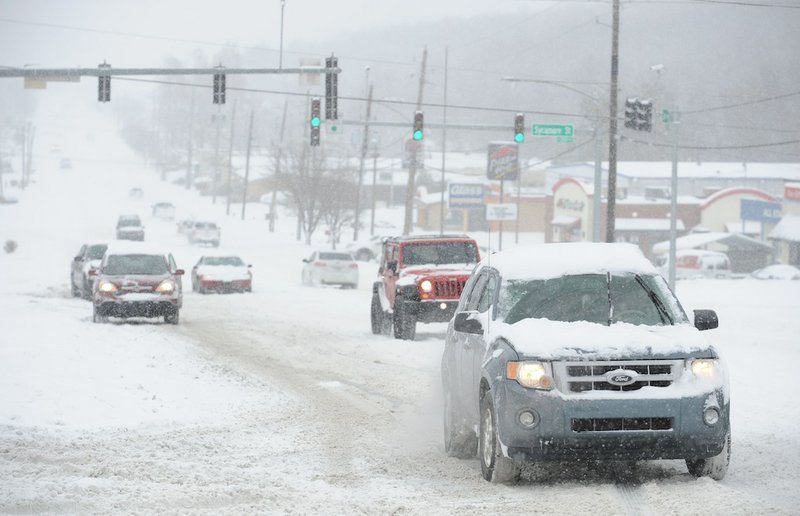 Motorists struggle to head south on North College Avenue at Sycamore Street as snow falls Friday, Dec. 6, 2013, in Fayetteville.