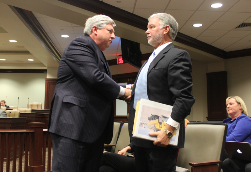 University of Arkansas trustee John Goodson, left, shakes hands with former fundraising division chief Brad Choate Friday after Goodson addressed a legislative audit panel.