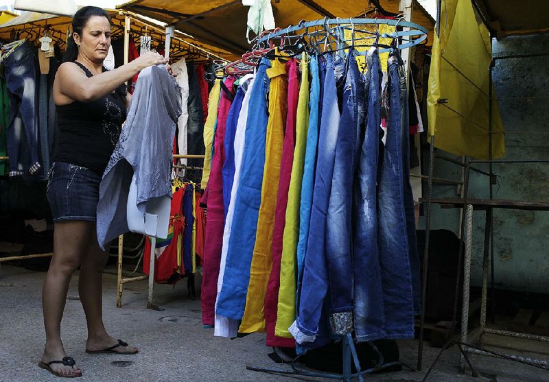Mabel Perez, 38, arranges a garment for display at an open-air market that specializes in clothing in Havana, Cuba, on Dec. 5. While the free market is still limited in Cuba, it is starting to alter lives and reshape social attitudes. 