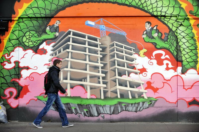 A pedestrian passes a mural Thursday depicting the stalled construction of Anglo Irish Bank Corp.’s headquarters in Dublin. The final portion of bailout funds for Ireland from the European Union and International Monetary Fund arrived this week. 