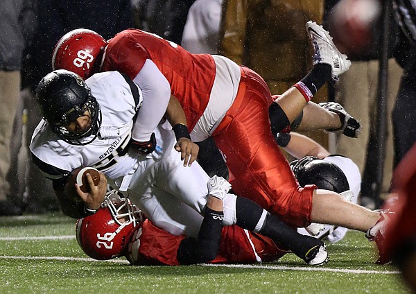 Bentonville's Dylan Smith is taken down by Cabot's Colby Ferguson, bottom, and Aaron Henry, top, as he makes a dash for the end zone during their championship game December 13, 2013 at War Memorial Stadium.