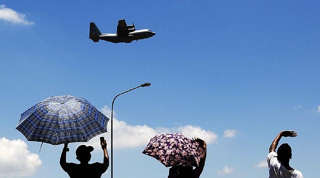 People wave at an aircraft carrying the casket of former South African President Nelson Mandela as it takes off from Waterkloof Air Base on the outskirts of Pretoria, South Africa, Saturday, Dec. 14, 2013.  On a final journey to his home village where he had wanted to spend his final days, the remains of Nelson Mandela were honored amid pomp and ceremony Saturday at an air base in South Africa's capital before being loaded onto a plane.  (AP Photo/Matt Dunham)