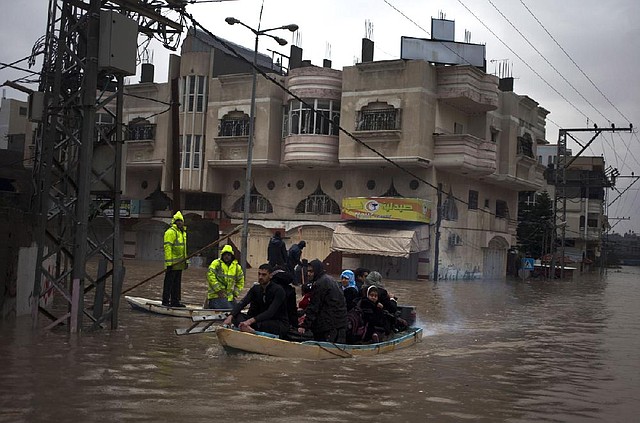 Palestinian rescue members evacuate residents using a fishing boat following heavy rains in Gaza City, Saturday, Dec. 14, 2013. Rescue workers evacuated more than 5,000 Gaza Strip residents from homes flooded by four days of heavy rain, using fishing boats and heavy construction equipment to pluck some of those trapped from upper floors, an official said Saturday. (AP Photo/Khalil Hamra)