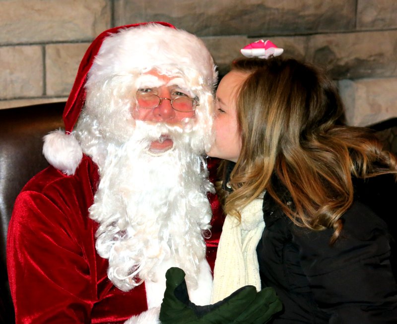 Photo by Randy Moll Alandrea Roberson leans over and gives Santa a kiss during his visit to the Gentry Chamber of Commerce building on Saturday.