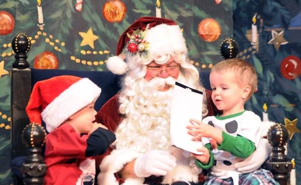 Jason Piech, 6, left, waits as Alex Piech, 4, offers Santa one of his stickers Saturday, Dec. 14, 2013, at the Arts Center of the Ozarks during the annual Breakfast with Santa event. Children got to take pictures with Santa, eat breakfast, make holiday crafts and decorate gingerbread cookies. The Arts Center of the Ozarks expected 500 people for the sold-out event.