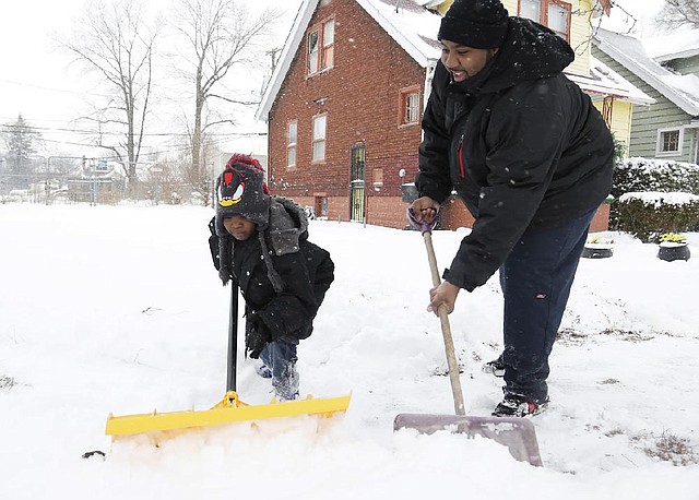 Keishard Hatcher, 6, left, helps his father Montez Gates, 29, shovel in front of their Monica Street home in Detroit after heavy snows covered the area Sunday Dec. 15, 2013. A pre-winter snowstorm continues to grip parts of Michigan, with accumulations already topping 9 inches in the state's southeastern corner. (AP Photo/Detroit Free Press, Mandi Wright)  DETROIT NEWS OUT;  NO SALES