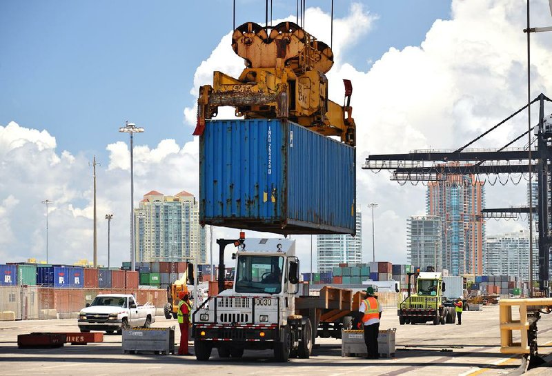 A container is lowered onto the trailer of a “yard mule” at the Dante B. Fascell Port of Miami-Dade County in Miami in August. The U.S. current account deficit narrowed in the July-September quarter, the Commerce Department said Tuesday. 