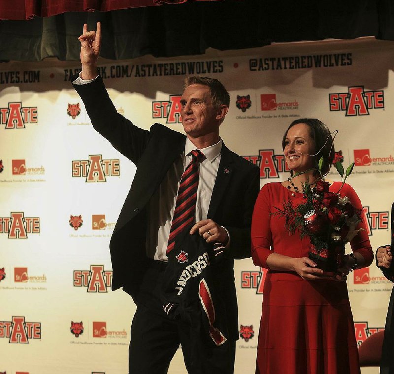  Arkansas Democrat-Gazette/STATON BREIDENTHAL --12/19/13-- New Arkansas State football coach Blake Anderson (left) along with wife Wendy flashes the Red Wolves sign as he holds an ASU football jersey Thursday afternoon at a press conference in Jonesboro.