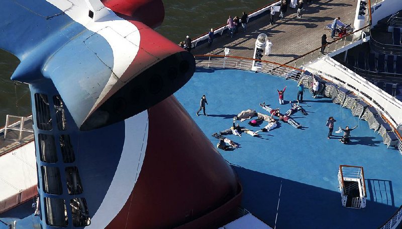 FILE - In this Thursday, Feb. 14, 2013, file photo, passengers spell out the word "HELP" aboard the disabled Carnival Lines cruise ship Triumph as it is towed to harbor off Mobile Bay, Ala. Carnival Cruise Lines knew about the risk of leaks from engine fuel hoses and recommended taking precautions on the ill-fated Carnival Triumph, which caught on fire at sea, according to documents filed in recent days. A "compliance notice report" sent to the Triumph one month before it departed Galveston on Feb. 7 for what was planned as a four-day cruise recommended spray shields be installed on engines' flexible fuel hoses, according to documents filed Tuesday, Dec. 17, 2013, by Carnival Cruise Lines in federal court in Miami. (AP Photo/Gerald Herbert, File)