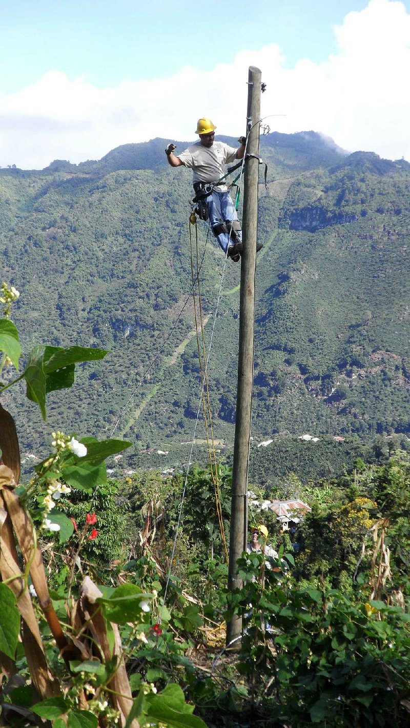 Special to the Arkansas Democrat-Gazette/ROB ROEDEL - 12/12/2013 - John Hawkins of First Electric Cooperative works at the top of a power pole in Guatemala and Ben Leslie of North Arkansas Electric Cooperative assists on the ground.