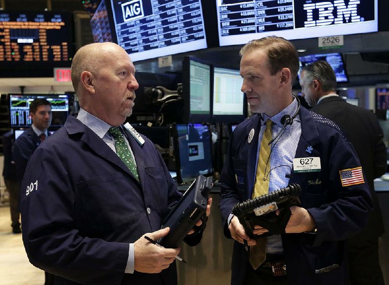 Traders John Doyle, left, and Michael Smyth confer on the floor of the New York Stock Exchange, Thursday, Dec. 19, 2013. Stocks edged lower in early trading Thursday, pulling back from record levels. (AP Photo/Richard Drew)