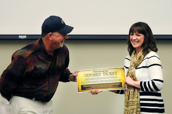 Amy Reeves Robinson, right, strategic partnerships for StartUp Cup, presents Rob Turner, of Turner Light Covers, with the Odyssey Ticket Thursday, Dec. 19, 2013, at the Bentonville Public Library during an awards ceremony for StartUp Cup. The Odyssey Tickets, presented to the winners of the local StartUp Cup competitions,  allows Turner to enter his business model into the World StartUp Cup competition held in March in Armenia.