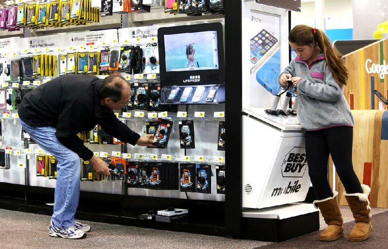 Arkansas Democrat-Gazette/MELISSA SUE GERRITS 12/19/13 - Ellie Fuller, 12, right, looks at an iPhone she hopes to get for Christmas as another shopper kneels to scouer shelves for iPhone cases December 19, 2013 at Best Buy off Chenal Parkway. 