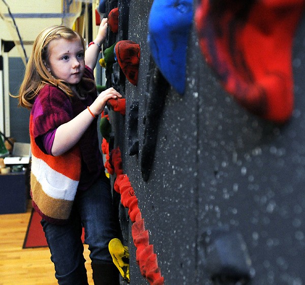 Teaghan Wolff, 6, works her way across the climbing wall dedicated to her father, Chad Wolff, Friday, Dec. 20, 2013, at Kirksey Middle School in Rogers. Wolff, a special education teacher at Kirksey, died in April while hospitalized for surgery. Funding for the climbing was was already in progress at the time of Wolff's death, but since Wolff was a supporter of the project and an athlete, the school decided to commemorate the climbing wall in Wolff's honor.