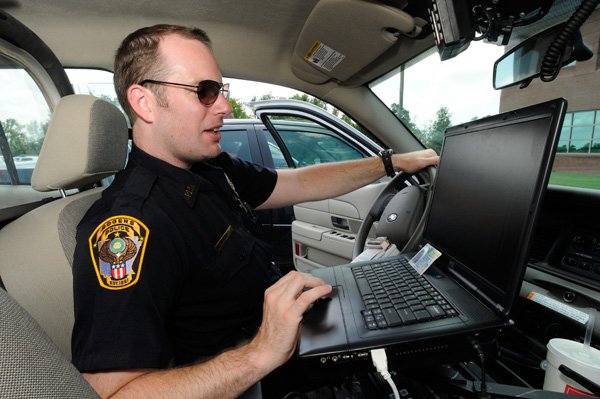 Officer Jamison Stiles shows how he can use his computer to check for warrants on a person in his squad car Thursday July 15, 2010 in Rogers. Rogers police officers must also serve warrants during their regular patrols. Stiles said he tries to check out two warrants each shift which allows his to check on 40 warrants a month.
