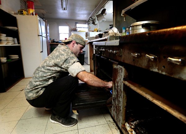 Resident Derrick Cara (cq) lights the pilot light on the stove to start cooking dinner for fellow residents on Thursday, Dec. 19, 2013, at Souls Harbor in Rogers. Souls Harbor is a transitional living facility which is building a new kitchen and dining facility to replace the current building.