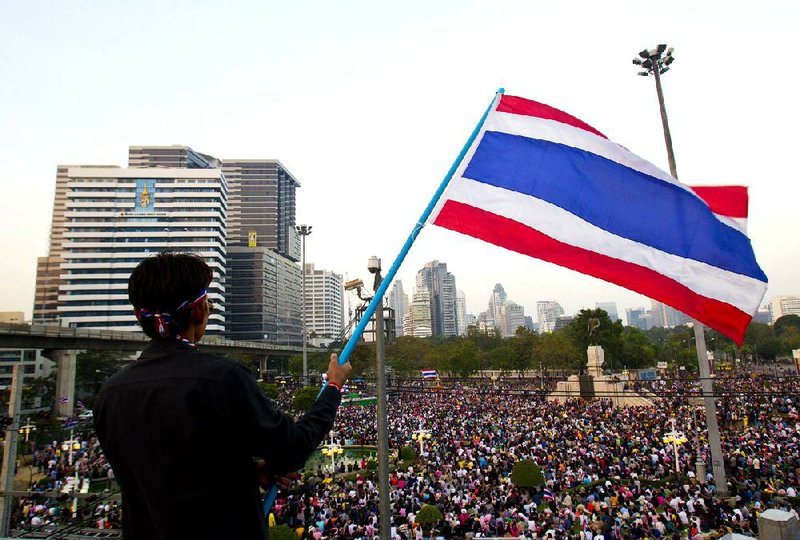 Thai anti-government protesters wave their national flag on Sunday, Dec. 22, 2013, in Bangkok, Thailand. Tens of thousands of protesters marched through Thailand's capital on Sunday, paralyzing traffic and facing off with police outside the prime minister's residence in their latest bid to force her from office. (AP Photo/Sakchai Lalit)