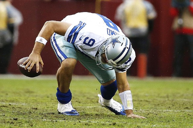 Dallas Cowboys quarterback Tony Romo slips on the turf while scrambling with the ball during the second half of an NFL football game against the Washington Redskins in Landover, Md., Sunday, Dec. 22, 2013. (AP Photo/Alex Brandon)