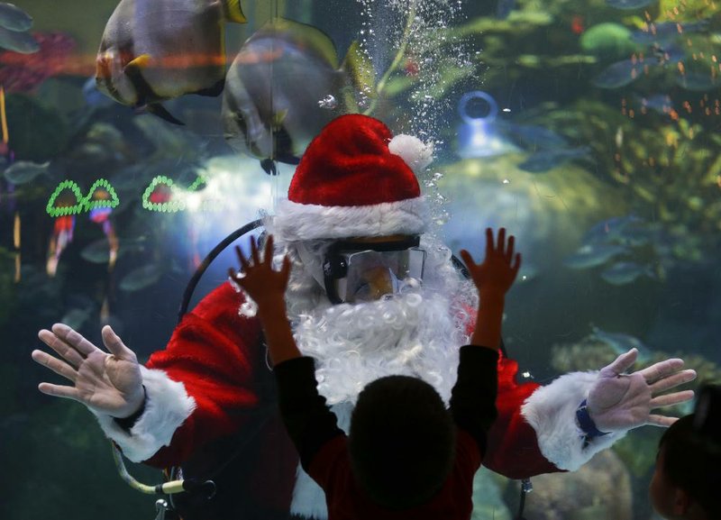 FILE - In this Sunday, Dec. 9, 2012, file photo, Jerry Cowley, aquatic safety manager at the Silverton Hotel-Casino interacts with children as an underwater Santa Claus, at the casino's aquarium in Las Vegas. In an attempt to lure tourists, Las Vegas casinos are staging increasingly elaborate holiday events.  (AP Photo/Julie Jacobson, File)