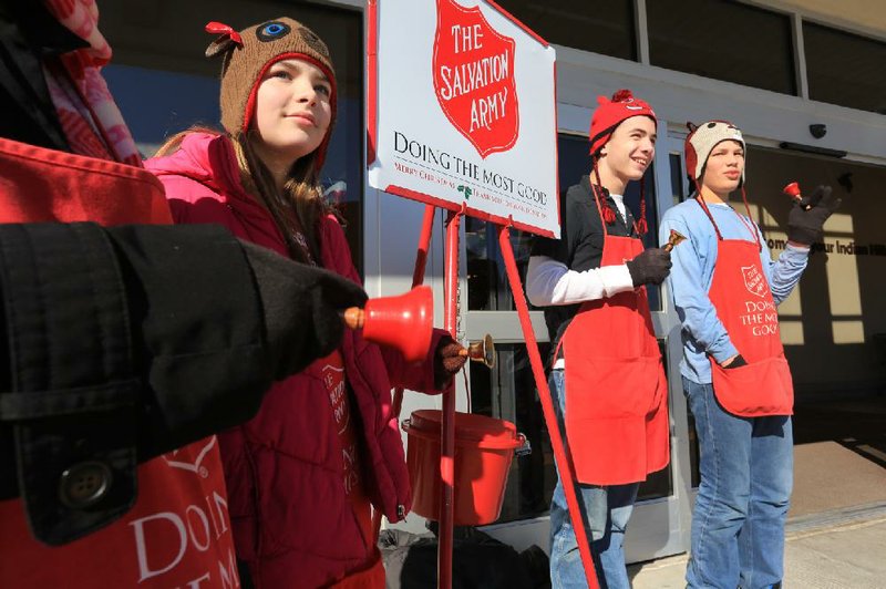 The Thompson family — which includes (from left) Lauren, 11, Joseph, 15, and Noah, 13 — volunteer to ring handbells for the Salvation Army’s Red Kettle Campaign outside the Indian Hills Kroger in North Little Rock on Christmas Eve, the last day of the fundraising campaign. They were accompanied by their bell-ringing mother, Jamie Thompson of North Little Rock (arm shown, left). 