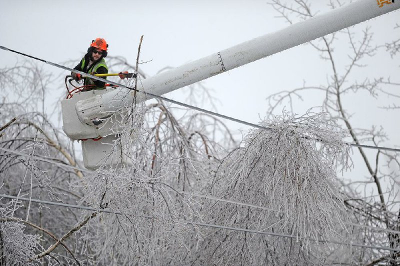 Andrew Powers, an arborist with Asplundh Tree Experts, clears iced branches from power lines in Waterville, Maine, on Monday. 