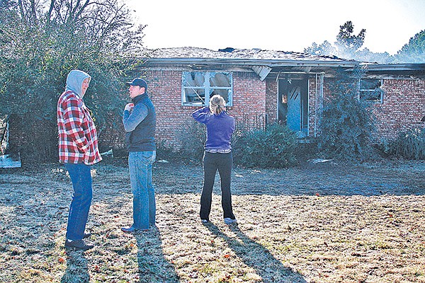 STAFF PHOTO DAN HOLTMEYER 
Bill Meissinger, left, and other relatives of Paul Pannell survey the damage at Pannell’s house Tuesday after a major fire destroyed everything but the brick walls. Pannell suffered only minor injuries after Meissinger, his son-in-law, smashed a ladder through Pannell’s bedroom window to get him out.