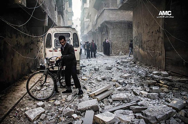 A Syrian walks in the rubble of buildings damaged in Aleppo by government forces in photo take Monday by the Aleppo Media Center. 