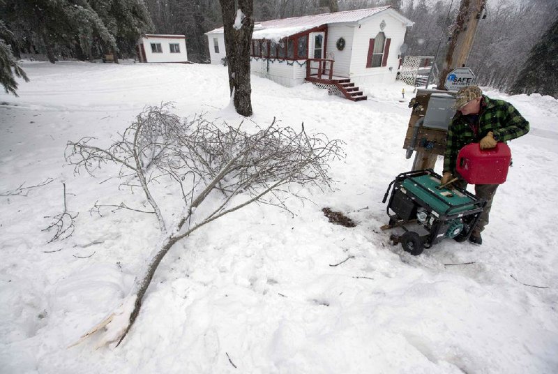 Brad Marquis adds gas to his generator outside his home, Thursday, Dec. 26, 2013, in Bowdoin, Maine.  Many people in the town have been without power for four days. Up to 7-inches of snow is forecast, worrying utilities that the additional weight on branches and transmission lines could cause setbacks in the around-the-clock efforts to restore power. (AP Photo/Robert F. Bukaty)