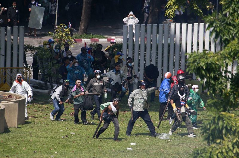 Thai anti-government protesters enter a sport stadium during a clash with riot policemen in Bangkok, Thailand, Thursday, Dec. 26, 2013. Rock-throwing protesters trying to halt preparations for elections fought police in the Thai capital on Thursday, escalating their campaign to topple the country's beleaguered government. (AP Photo/Wason Wanichakorn)