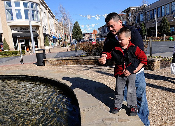 SHOPPING WISH 
While his wife and daughter shop, Rago Sanchez of Rogers and his son, Giovanni, 3, make a wish at a fountain on Thursday Dec. 26 2013 at Pinnacle Hills Promenade in Rogers.