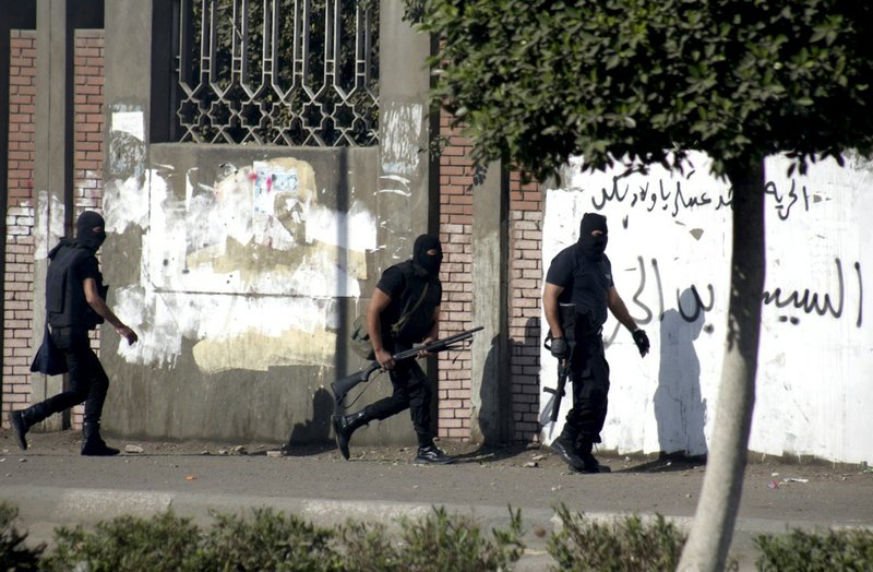 Masked Egyptian police move into position during clashes with supporters of ousted President Mohammed Morsi at the Islamic Al-Azhar University on Friday, Dec. 27, 2013. 