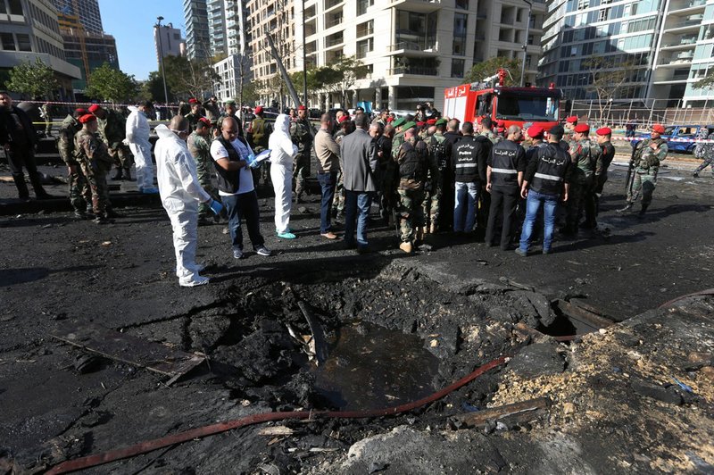 Lebanese army investigators in white coveralls stand next to a blast crater at the scene of an explosion in Beirut, Lebanon, Friday, Dec. 27, 2013. A powerful car bomb tore through a business district in the center of the Lebanese capital Friday, killing Mohammed Chatah, a prominent pro-Western politician and at least five other people. 