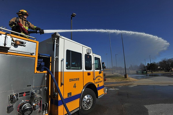 Springdale probationary firefighter Osburn Lawson works the water cannon during a training exercise Thursday afternoon at J.B. Hunt Park in Springale.  Springdale firefighters took advantage of the weather temperatures rising above freezing to allow some of their new firefighters to train on on different equipment on the fire engines.