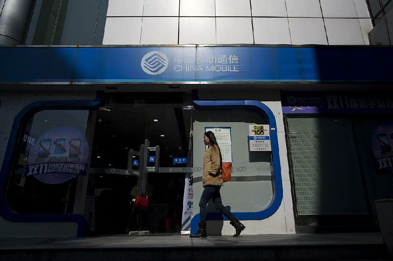 A woman walks past a China Mobile Ltd. store in the Luohu district of Shenzhen, China, on Thursday, Dec. 19, 2013. Apple Inc., ending six years of negotiations, struck a deal to sell the iPhone through China Mobile, giving both companies a means to fight declining share in the market of 1.2 billion wireless subscribers. Photographer: Brent Lewin/Bloomberg