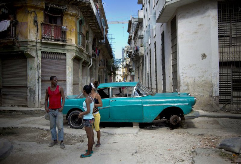 People talk as they stand in a street blocked by a broken down classic car in Havana, Cuba, Thursday, Dec. 26, 2013. The Associated Press recently checked in with nine small business owners whose fortunes it first reported on in 2011 as they set up shop amid the excitement of President Raul Castros surprising embrace of some free enterprise. Their fates tell a story of divided fortunes. (AP Photo/Ramon Espinosa)