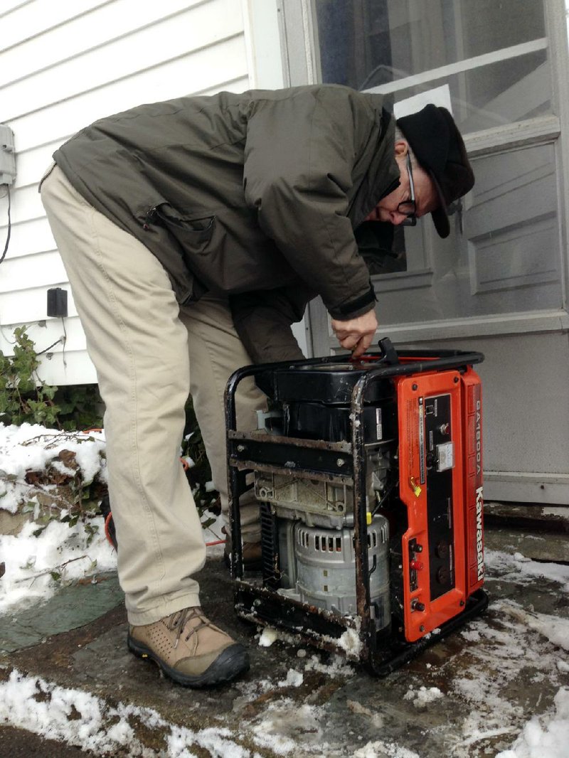 John Johnson, of East Lansing, Mich., works to hook up a generator he borrowed from a neighbor to heat his house on Friday, Dec. 27, 2013. As of Friday morning, Johnson had been without power since Sunday because of an ice storm. (AP Photo/David Eggert)