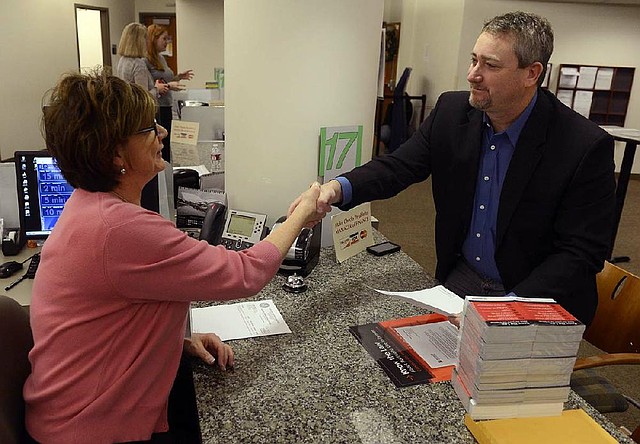 Shawn Phillips, right, owner of Strainwise marijuana stores, shakes hands with Denver Excise and License technician, Jennifer Scott, Friday, Dec. 27, 2013 after receiving his license to legally sell marijuana at the Wellington E. Webb Municipal Office Building in Denver, Colo. The city is giving out licenses to the owners of 42 medical marijuana shops and growers Friday. (AP Photo/The Denver Post, Andy Cross)