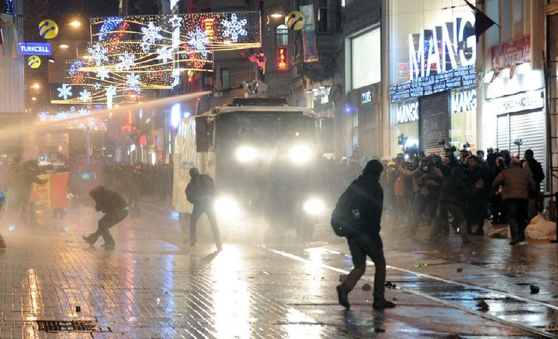 Protesters run as riot police use water cannons in Istanbul, Turkey, Friday, Dec. 27, 2013. Turkish Prime Minister Recep Erdogan on Friday faced mounting accusations of trying to cover up a corruption scandal that has implicated his allies after a prosecutor said he was being prevented from expanding a corruption probe. Erdogan was forced to reshuffle his government this week after three ministers, whose sons were detained as part of the probe, resigned. (AP Photo/Emrah Gurel)